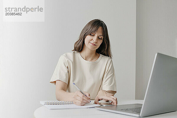 Businesswoman writing in diary and working at home office