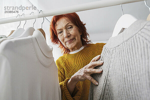 Senior woman with tops hanging on rack in closet