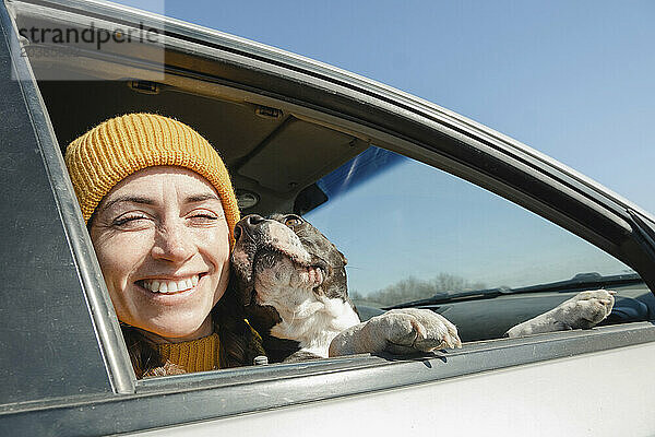 Happy woman sitting with dog in car