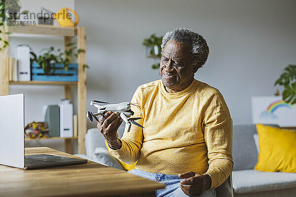 Smiling senior man learning to operate drone at home