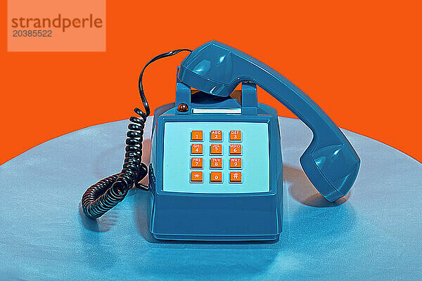 Retro style telephone on table against orange background