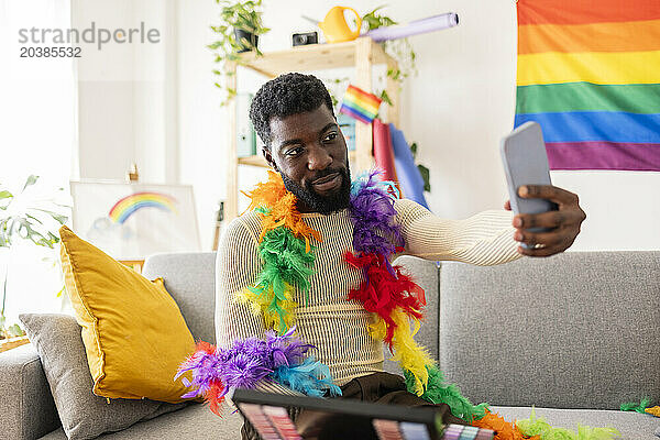 Young non-binary person taking selfie with feather boa at home