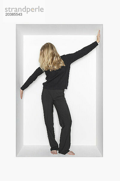 Blond teenager standing in alcove against white background