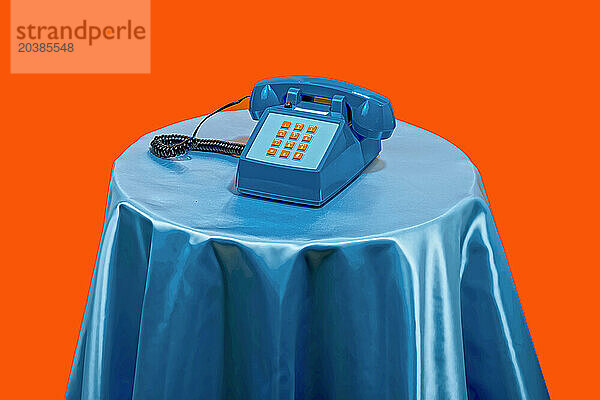 Vintage style telephone on table against orange background