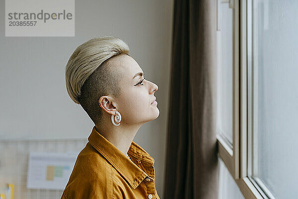 Lonely woman looking out of window at home