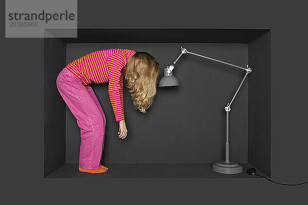 Blond teenage girl standing in front of electric lamp