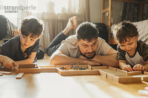 Father and sons playing leisure games on floor at home