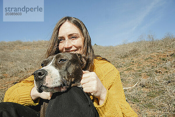 Happy woman sitting with dog on hill