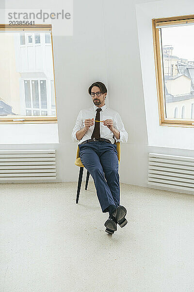 Businessman relaxing on chair amidst windows in office