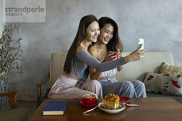 Friends taking selfie through smart phone at restaurant