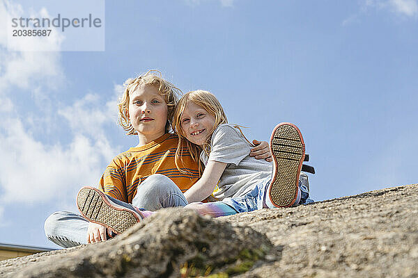 Boy sitting with sister on rock