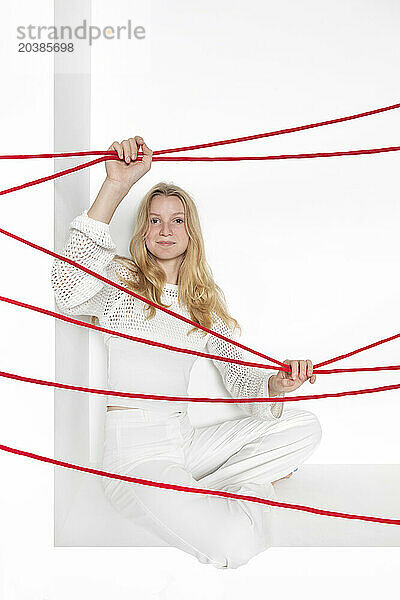 Blond teenage girl with red thread sitting in alcove