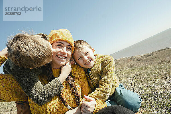Happy woman spending leisure time with sons on hill at sunny day