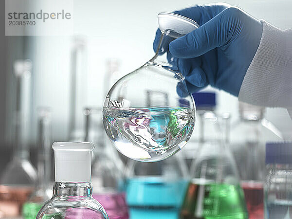 Senior scientist mixing chemical in round bottom flask at laboratory