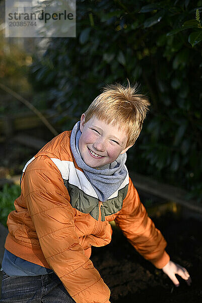 Smiling boy wearing jacket in garden