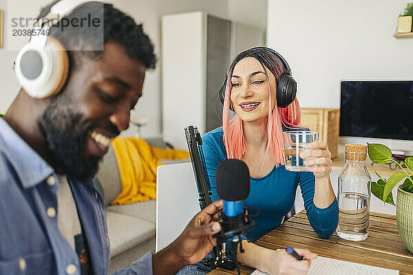 Happy influencers recording podcast in living room at home