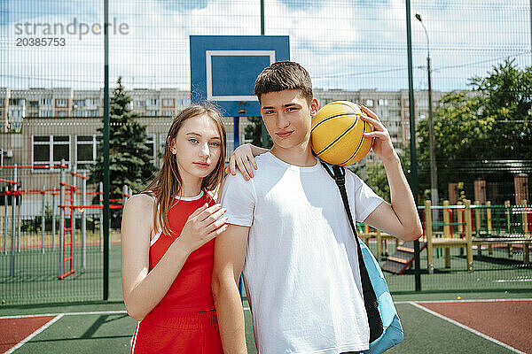 Teenage boy standing with friend in school yard