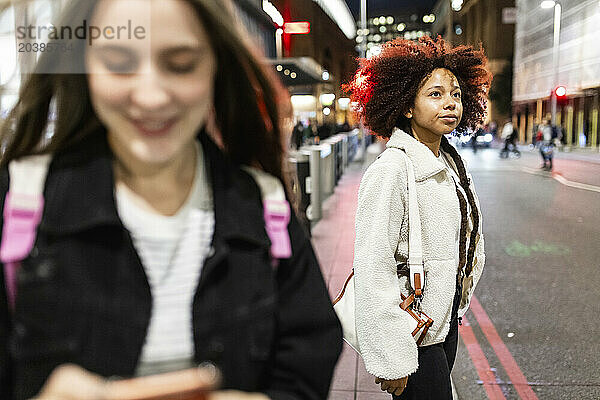 Thoughtful young woman standing near friend on street