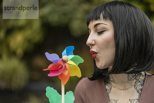 Woman with black hair blowing pinwheel toy