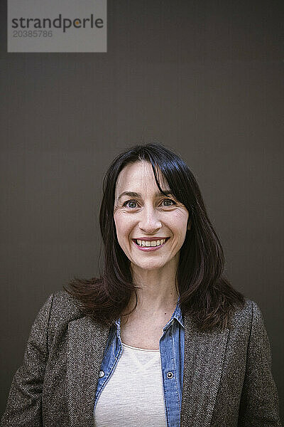 Smiling mature businesswoman against brown background