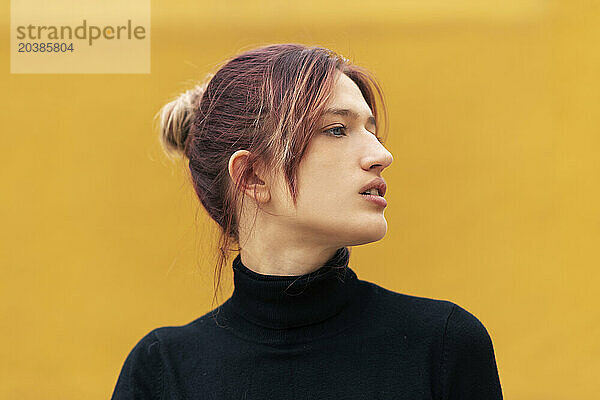 Beautiful young woman with dyed hair against yellow background