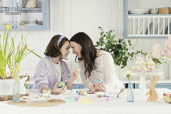 Mother and daughter with face to face celebrating Easter at home