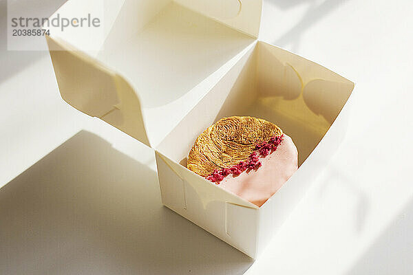 Circular croissants with pink chocolate and freeze-dried raspberries white take away box