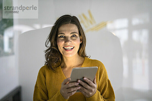 Smiling creative businesswoman holding tablet PC in office