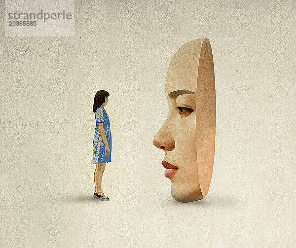 Woman standing in front of oversized mask against beige background