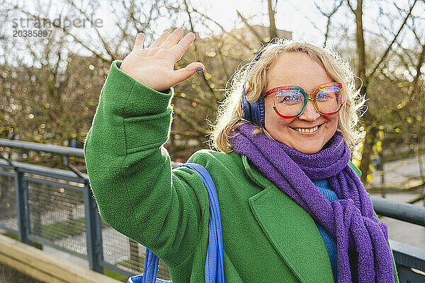 Smiling woman wearing wireless headphones and making high-five gesture