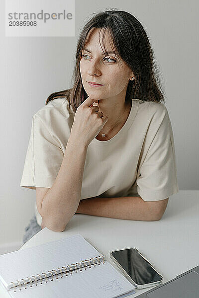 Thoughtful businesswoman with hand on chin in home office