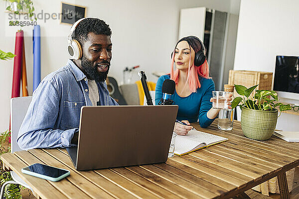 Influencers recording podcast at desk in home