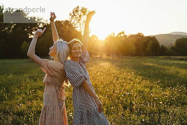 Carefree women with hands raised standing in park