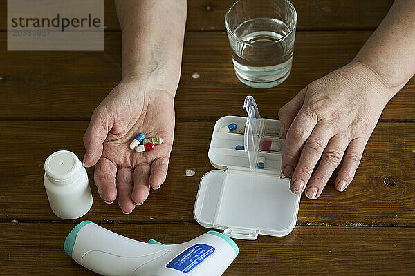 Hands of senior woman with capsules and pills on table at home