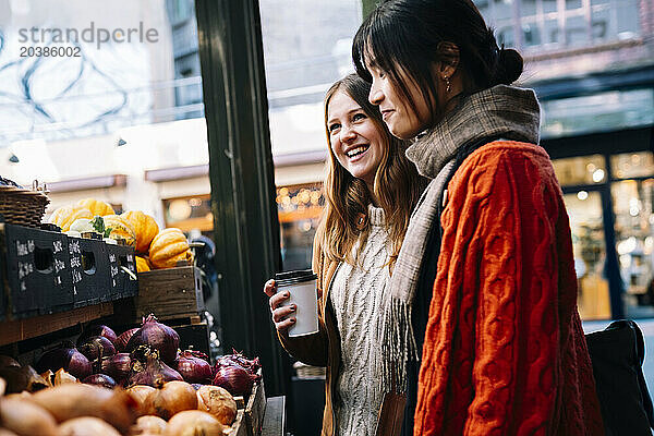 Happy sisters buying vegetables at market stall