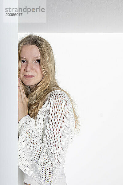 Blond teenage girl standing against white background