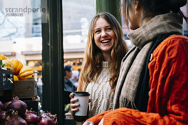 Happy woman talking to sister at market