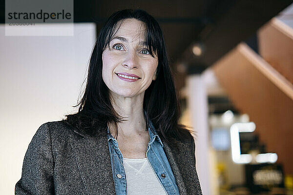 Thoughtful businesswoman smiling at office