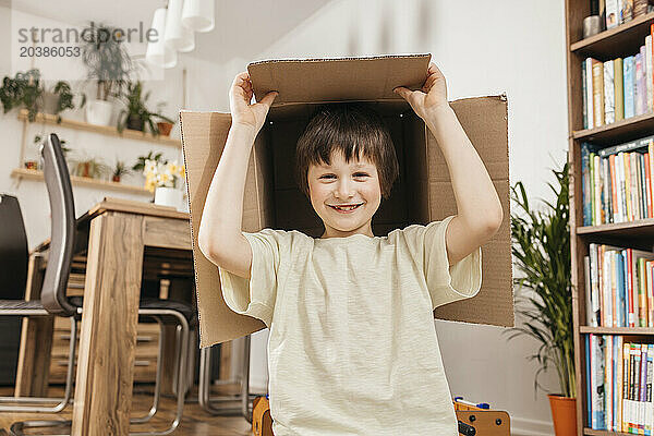 Happy boy holding cardboard box at home