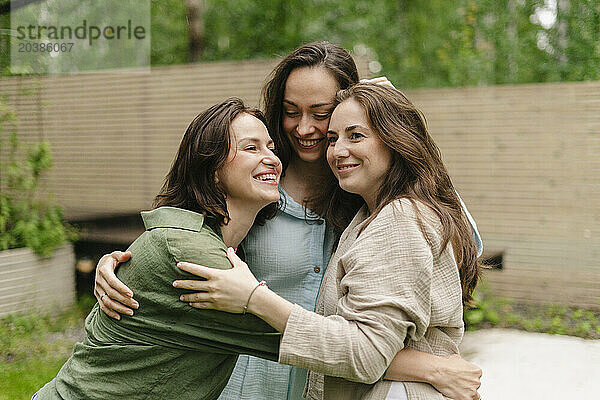 Happy friends embracing together in back yard