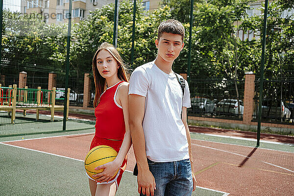 Basketball player standing with friend in schoolyard