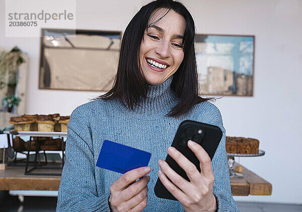 Happy woman making online payment through smart phone at store