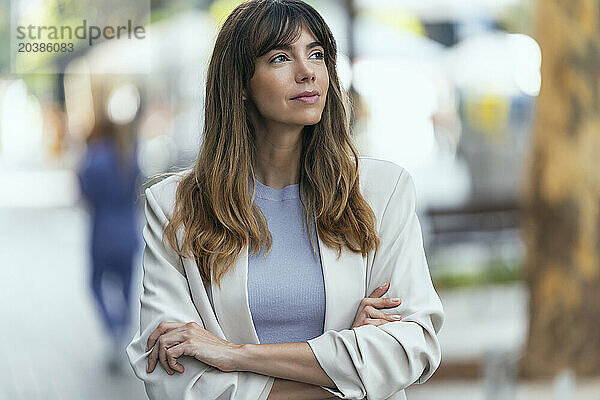 Thoughtful businesswoman standing with arms crossed