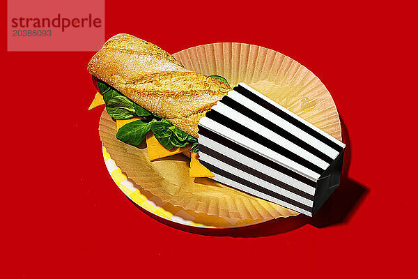 Cheese sandwich in paper container on red background