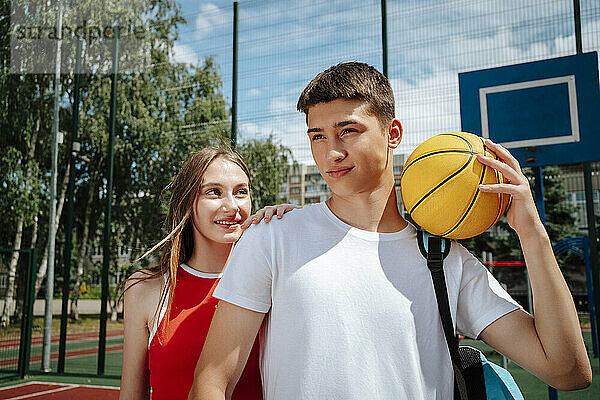 Confident boy holding ball near friend in school yard