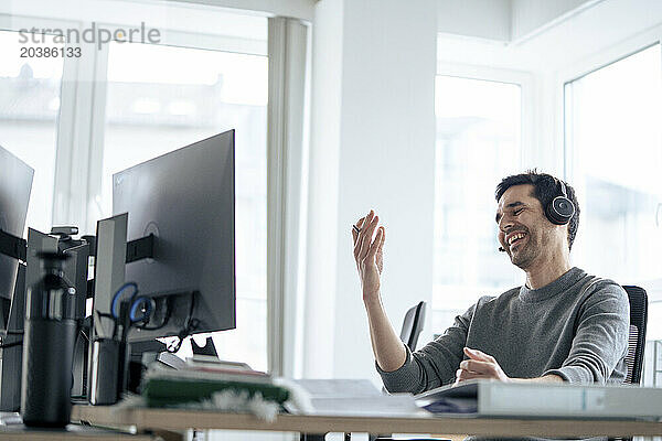 Happy businessman wearing headset and talking in office