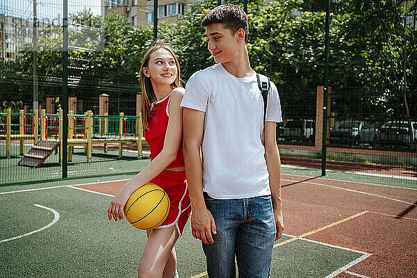 Smiling basketball player standing with friend in schoolyard