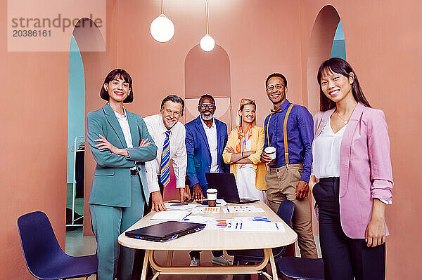 Confident multi-ethnic business team posing under illuminated light at office