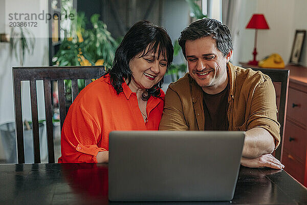 Smiling mother and son using laptop at home