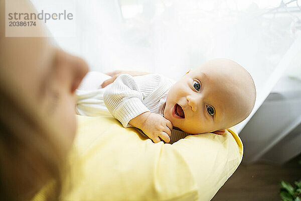 Cute boy with mother by window at home